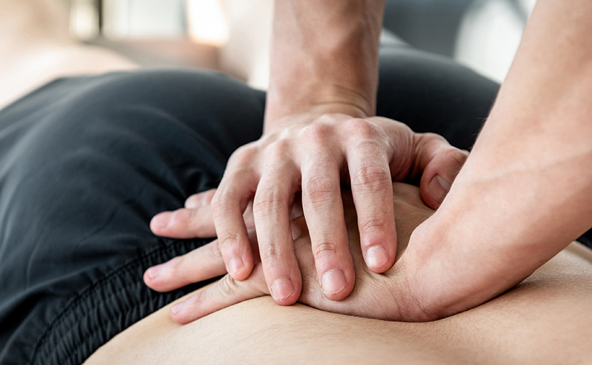 Therapist giving lower back sports massage to athlete
